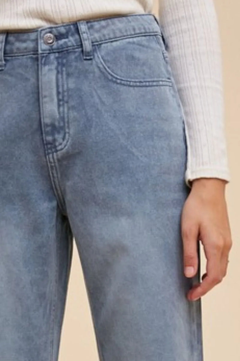 Light blue jeans worn by a person on a beige background