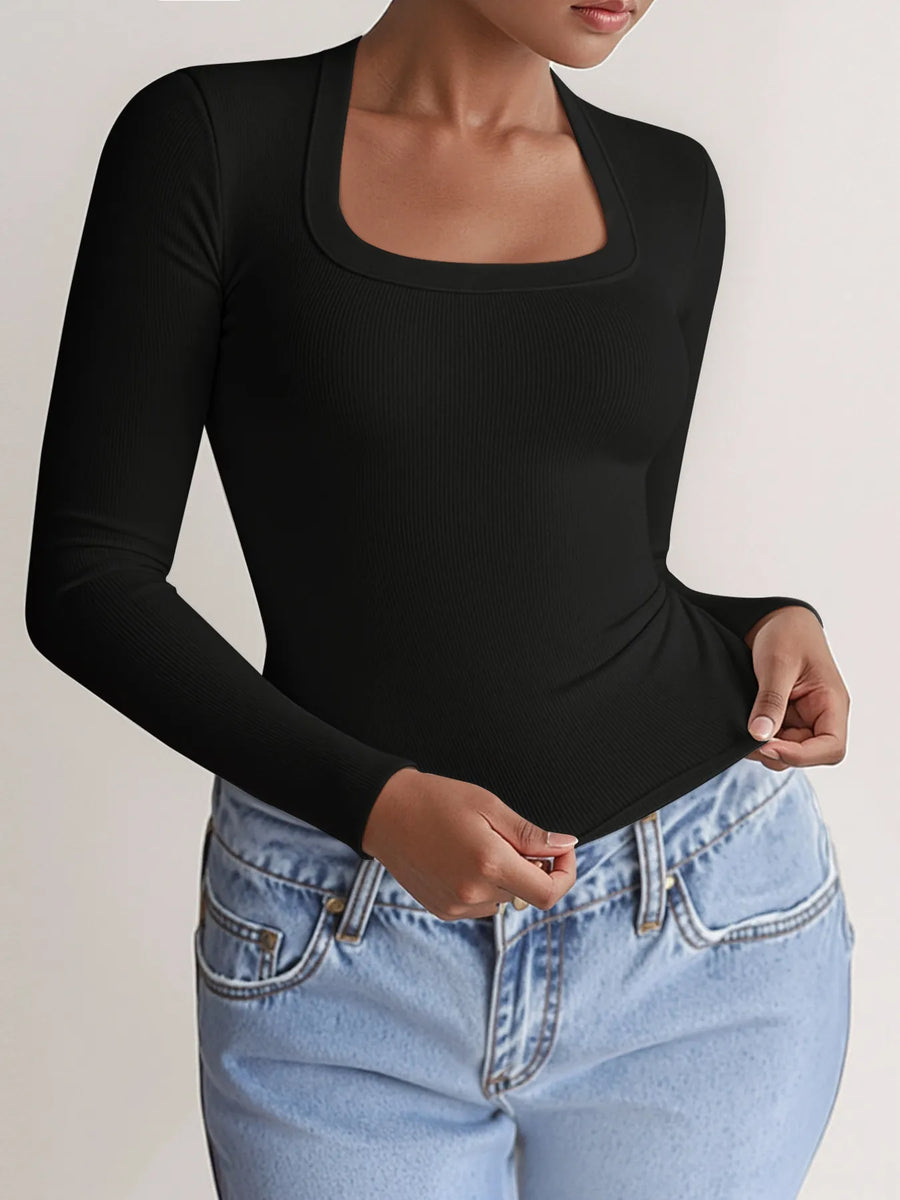 Person wearing a black long-sleeve top and light blue jeans on a plain background
