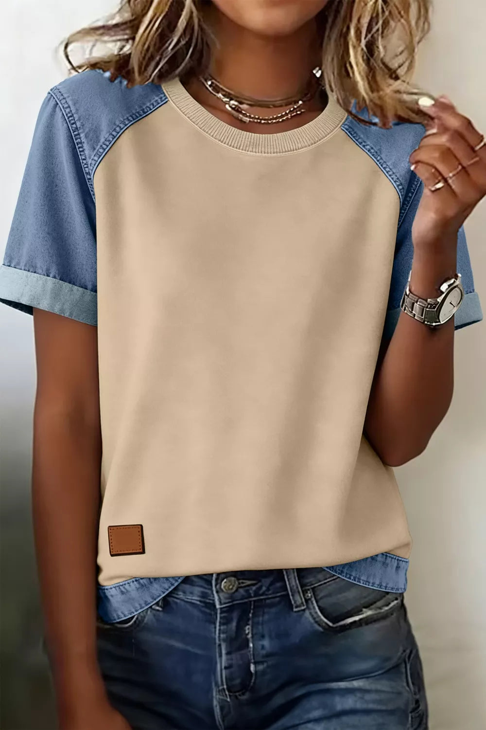 Person wearing a beige and blue baseball shirt with denim jeans.