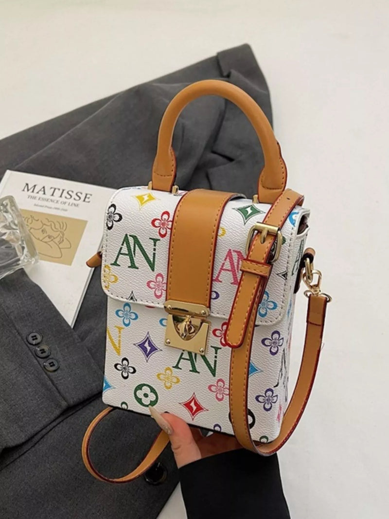 Handbag with colorful monogram design held over a gray garment and Matisse magazine.