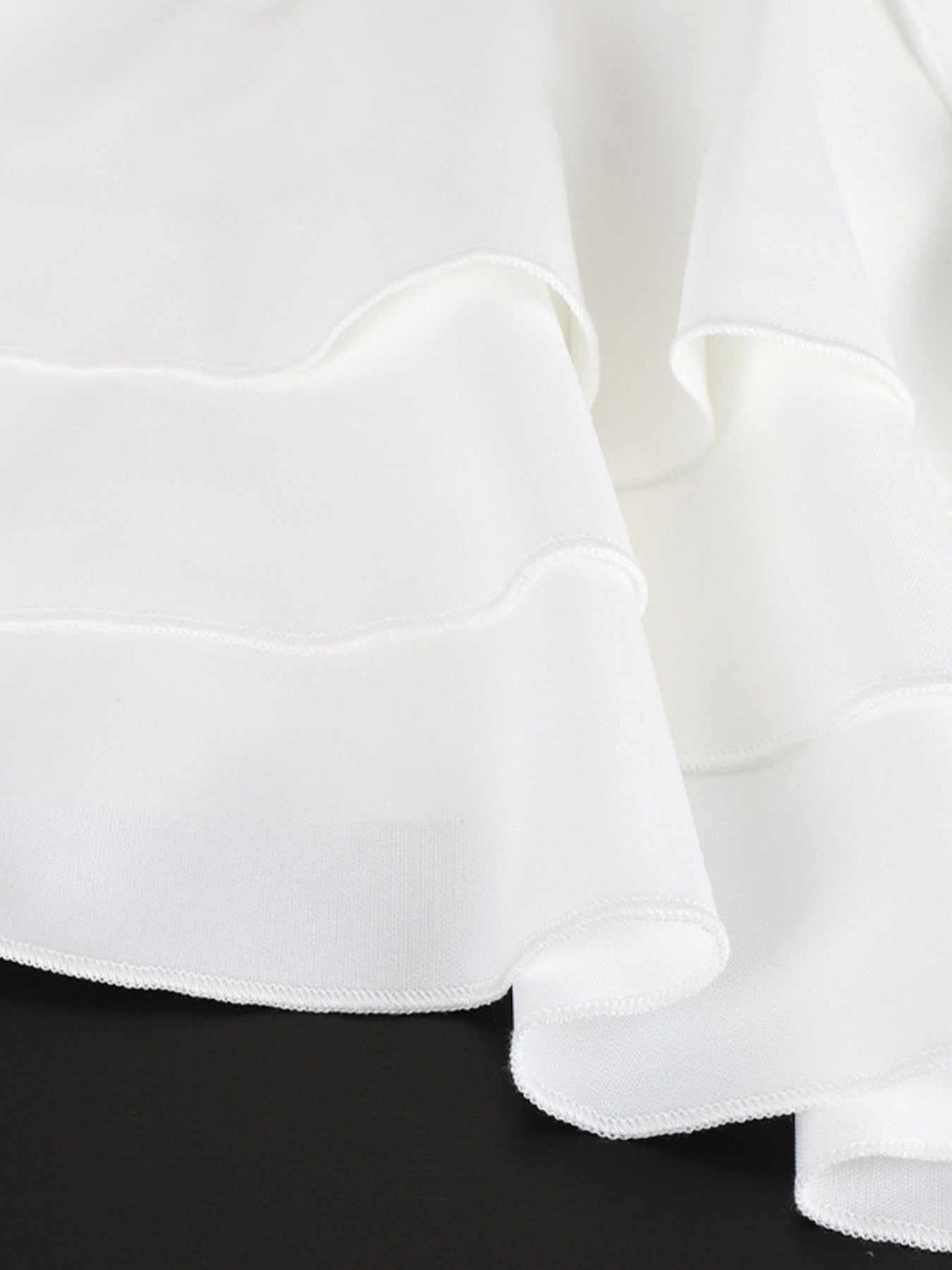 Close-up of white fabric with ruffled edges on a black background
