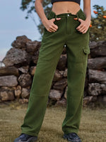 Person wearing green cargo pants standing in front of a stone wall.