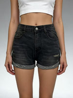 Person wearing black denim shorts with a white top on a gray background