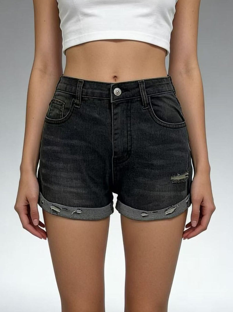Person wearing black denim shorts with a white top on a gray background