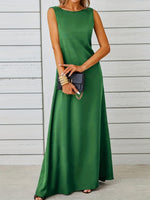 Woman wearing a green dress holding a black clutch against a wooden background