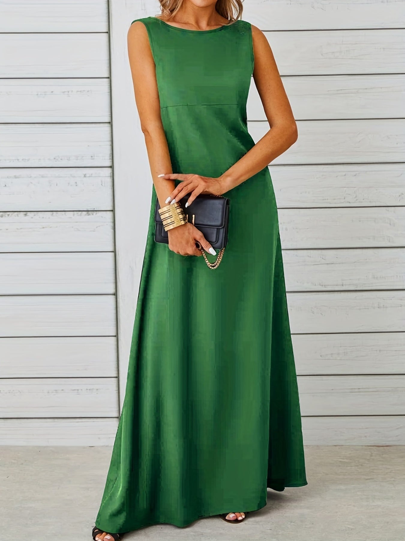 Woman wearing a green dress holding a black clutch against a wooden background