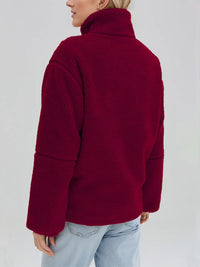 Person wearing a red fleece jacket on a plain background