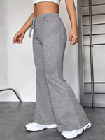 Person wearing gray flared pants and white sneakers in a minimal indoor setting