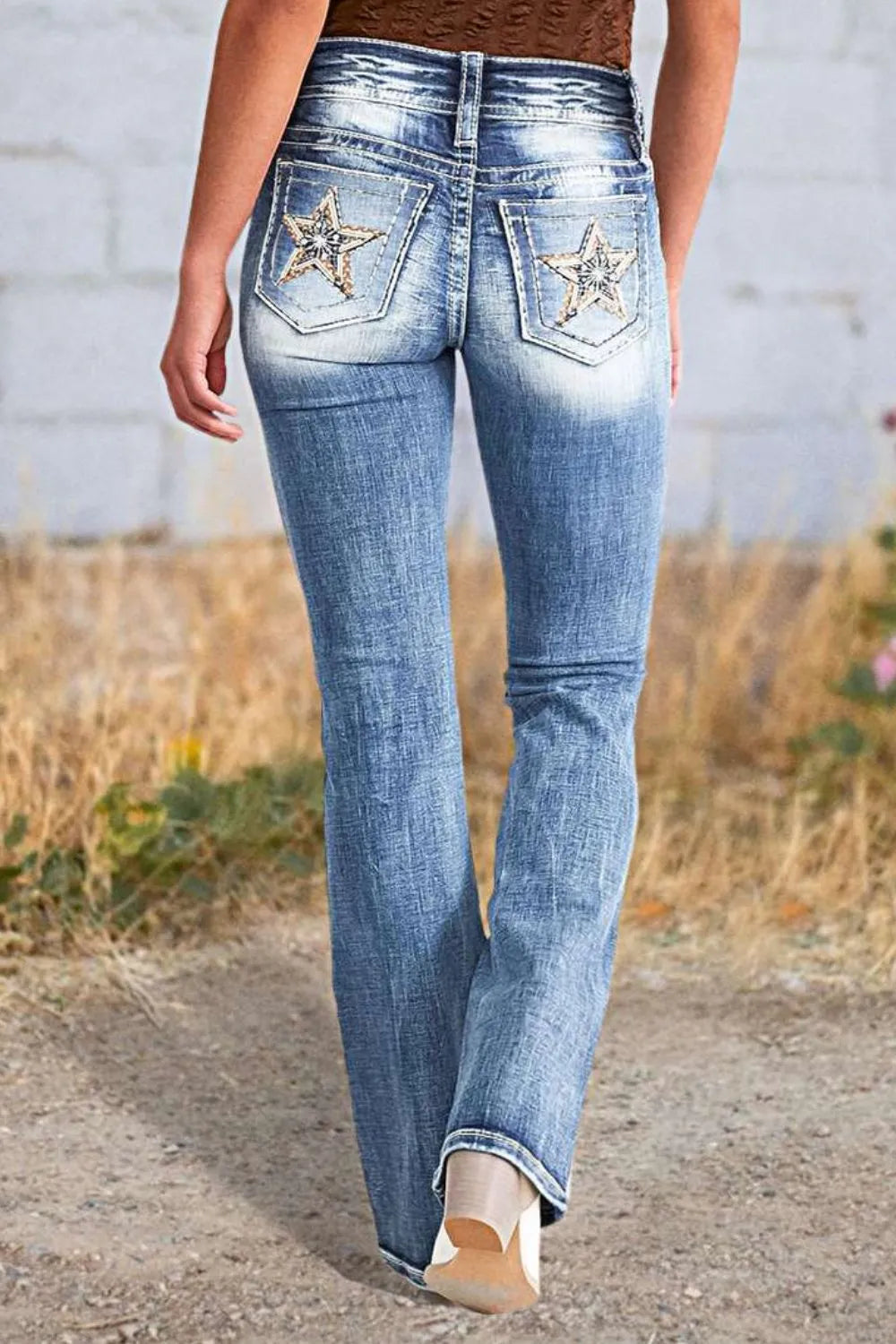 Person wearing blue jeans with star designs on a natural background