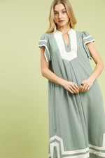 Woman wearing a green dress with white accents on a light green background