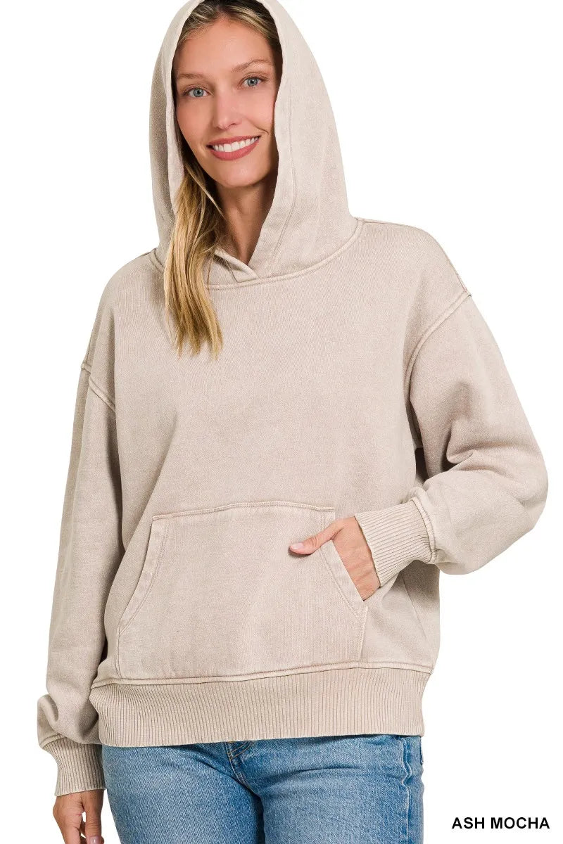 Woman wearing a beige hoodie with a plain background