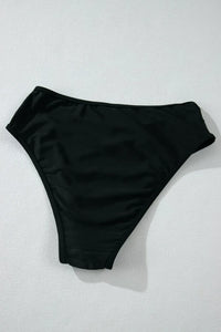 Black bikini bottom on a light gray background