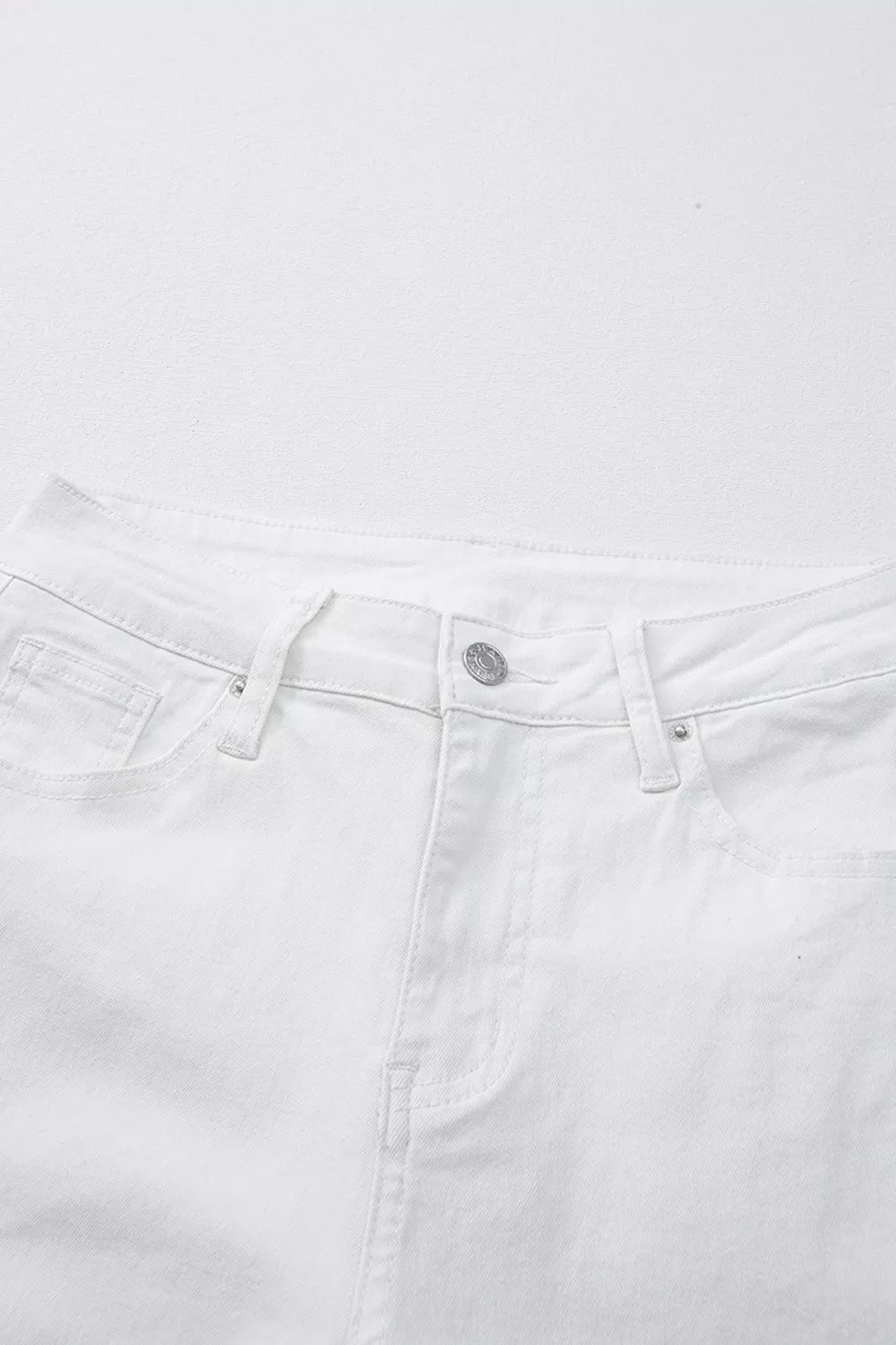 Close-up of white jeans with a visible brand logo on a white background