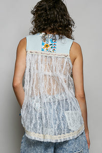 Person wearing a light blue sleeveless top with floral patterns on the back, standing against a plain background.