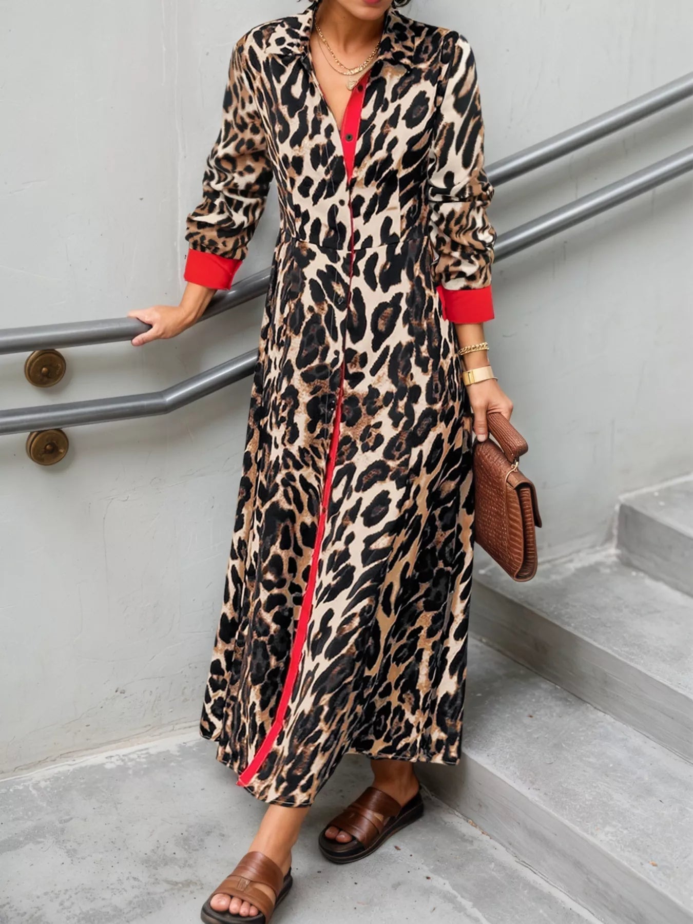 Person wearing a leopard print dress with red accents on a staircase.