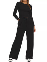 Person wearing a black long-sleeve top and wide-leg pants on a white background
