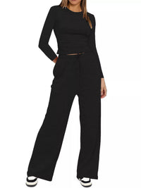 Person wearing a black long-sleeve top and wide-leg pants on a white background