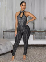 Woman in a black and silver jumpsuit posing in an elegant room.
