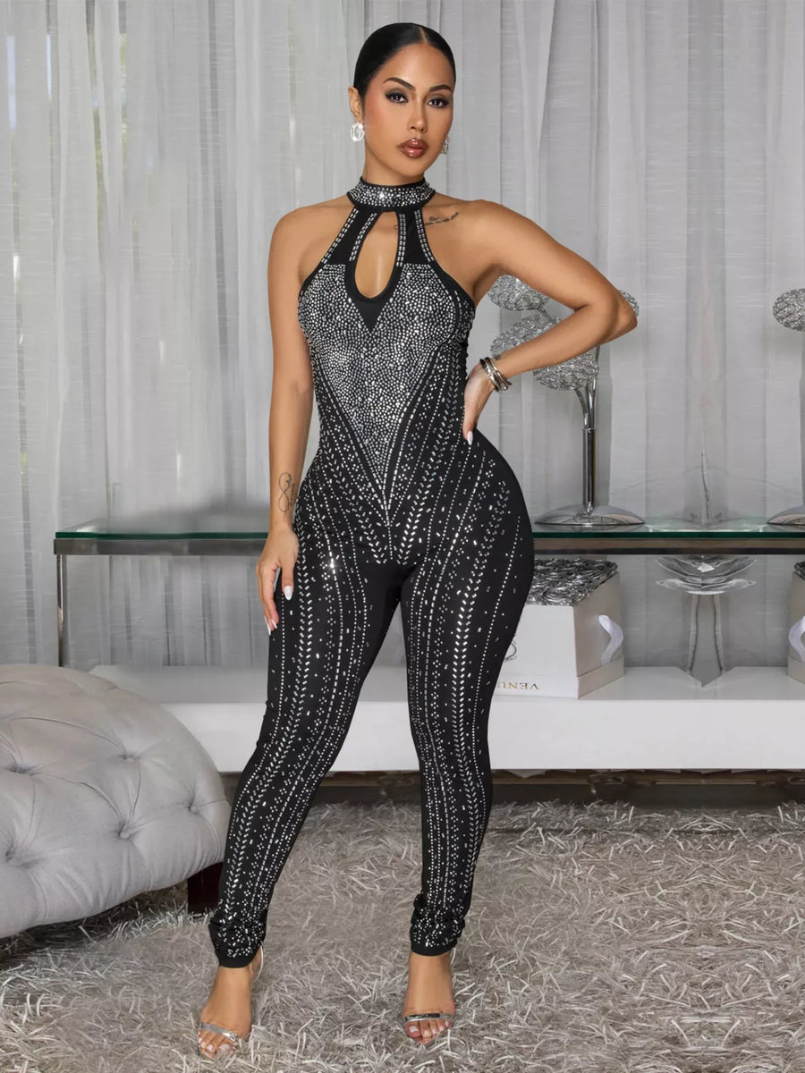 Woman in a black and silver jumpsuit posing in an elegant room.