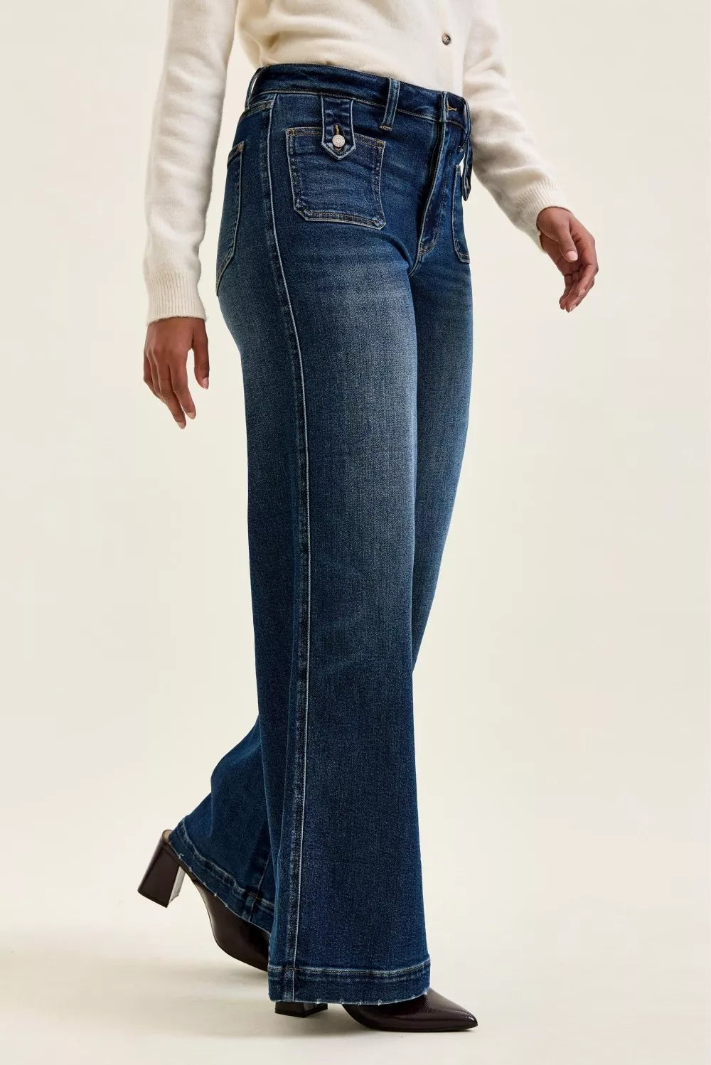 Person wearing blue flared jeans on a plain background