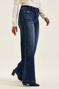 Person wearing blue flared jeans on a plain background