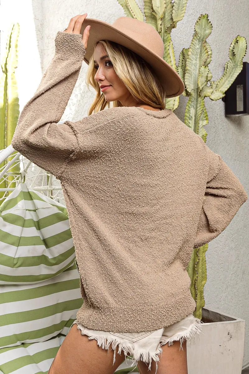 Woman wearing a beige sweater and hat in front of cacti