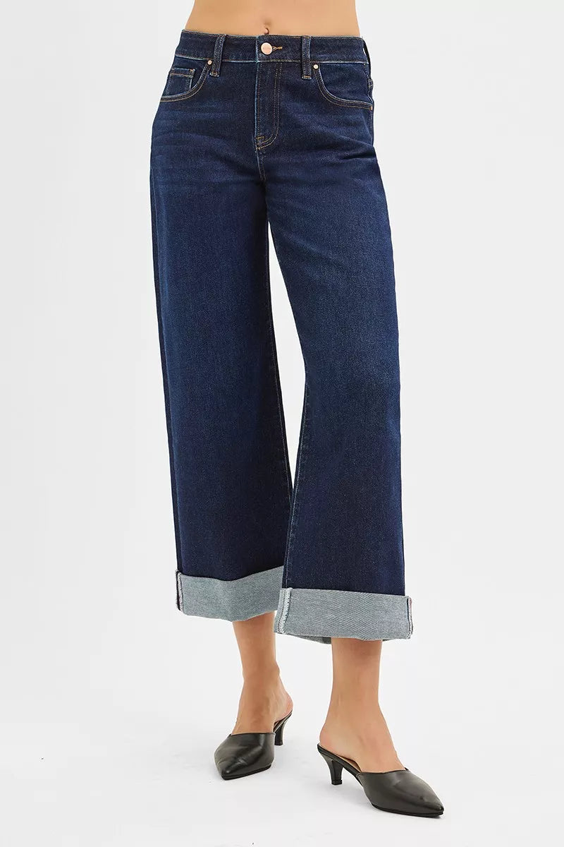 Dark blue wide-leg jeans worn by a person on a white background