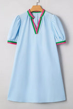 Light blue dress with colorful trim on a wooden hanger against a neutral background