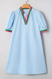 Light blue dress with colorful trim on a wooden hanger against a neutral background