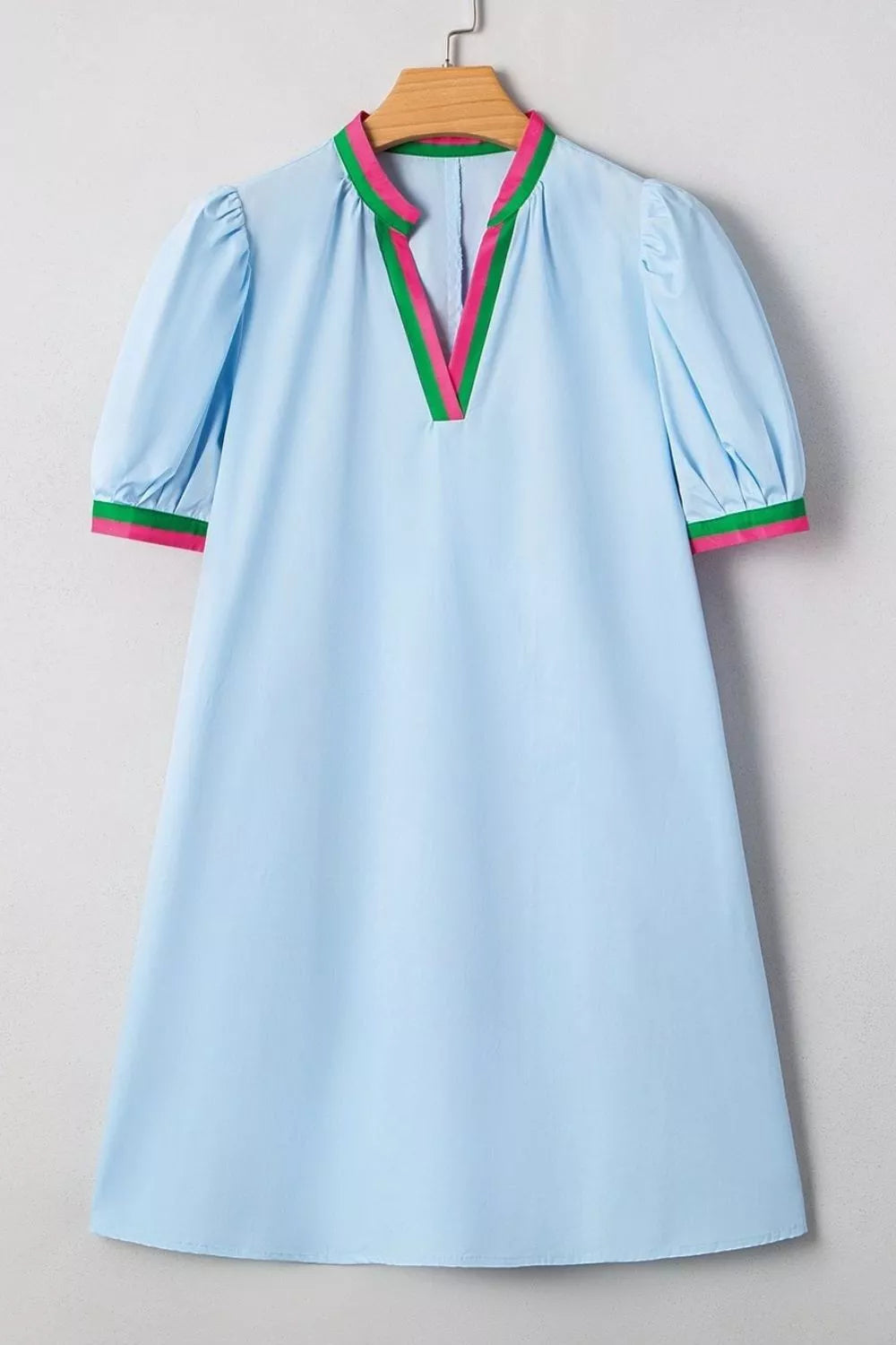 Light blue dress with colorful trim on a wooden hanger against a neutral background