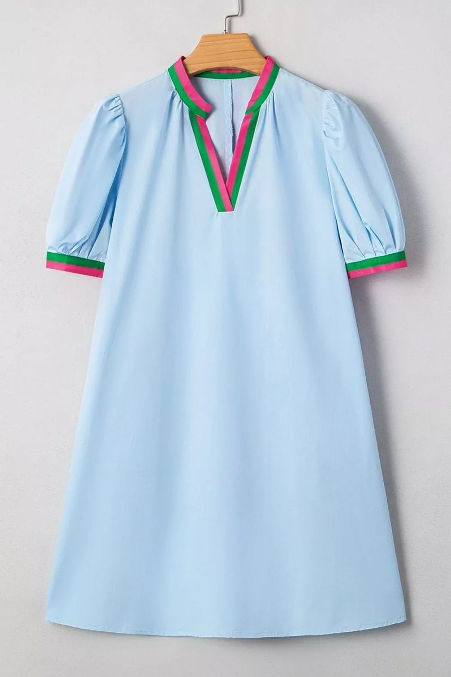 Light blue dress with colorful trim on a wooden hanger against a neutral background
