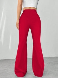 Red flared pants worn by a person on a plain background