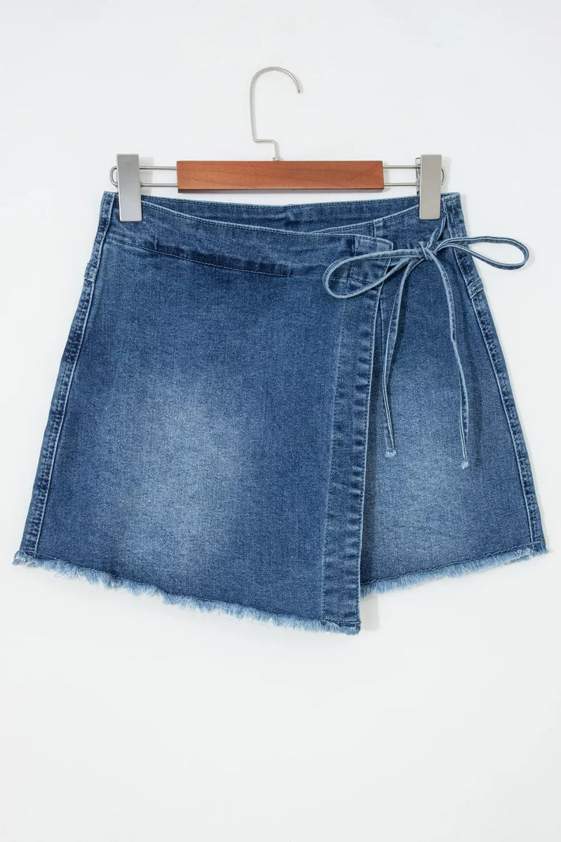 Blue denim skirt on a hanger against a white background