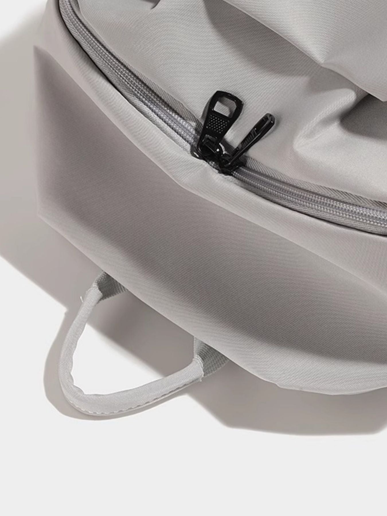 Close-up of a gray backpack with a zipper on a white background