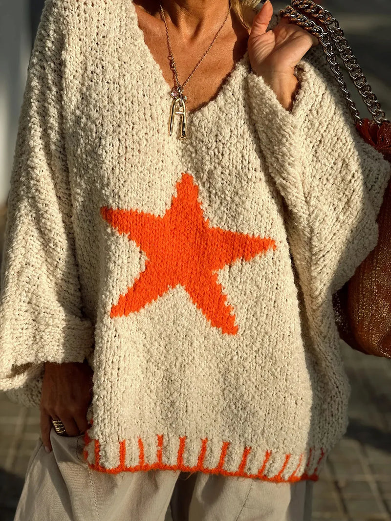 Person wearing a beige sweater with an orange star design.