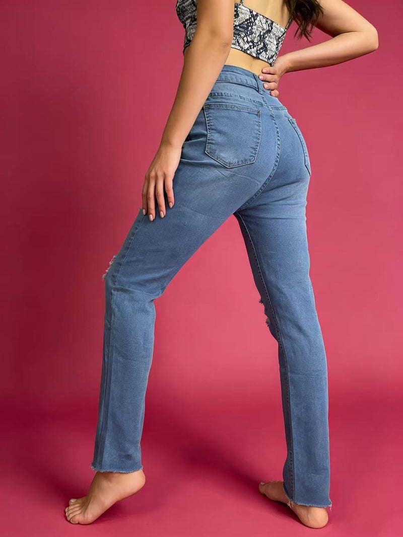 Person wearing blue jeans against a pink background