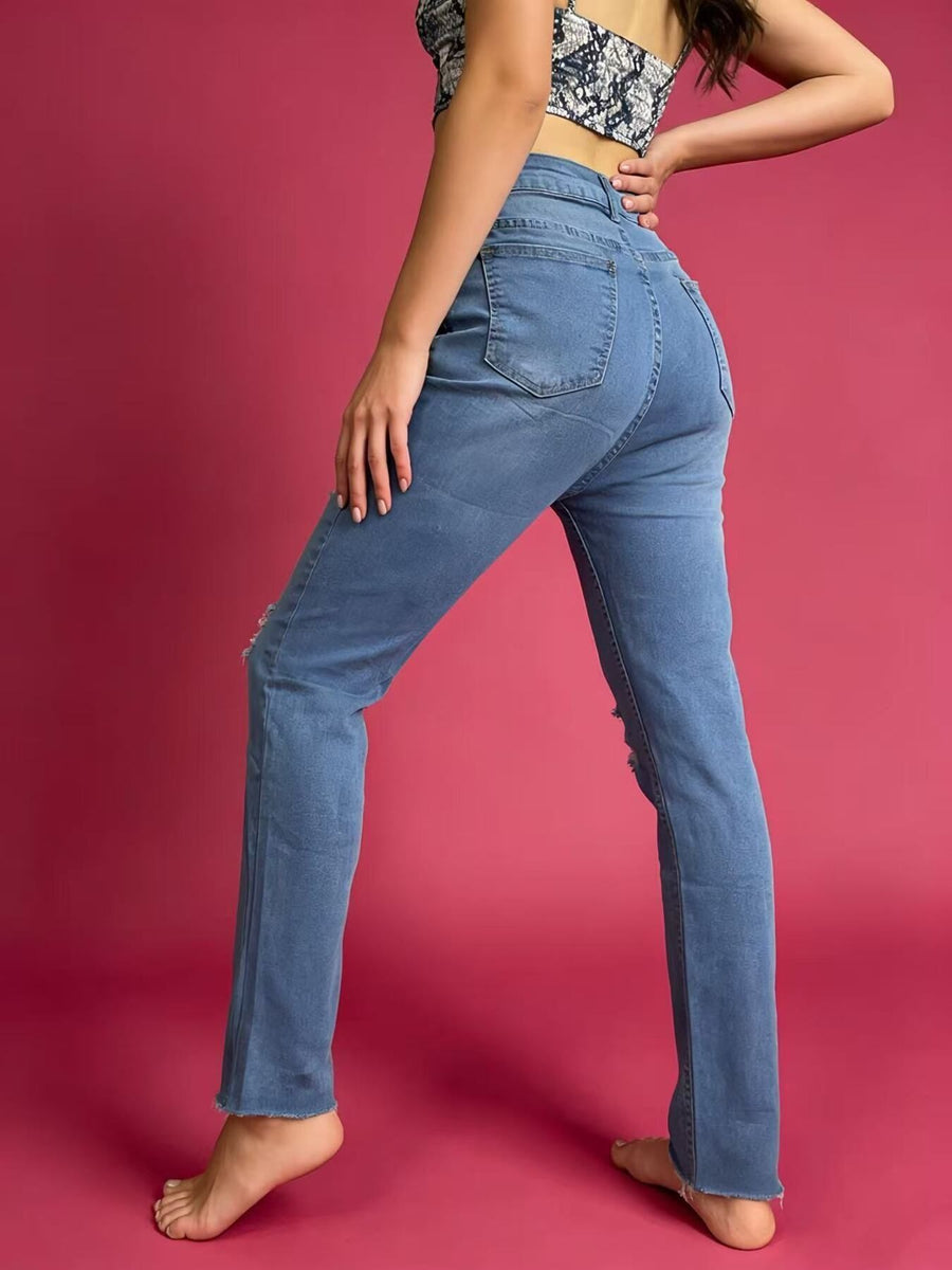 Person wearing blue jeans against a pink background