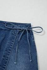 Blue denim skirt with tie waist on a light gray background