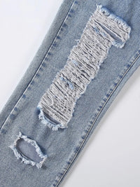 Distressed denim jeans with a large hole in the knee on a white background