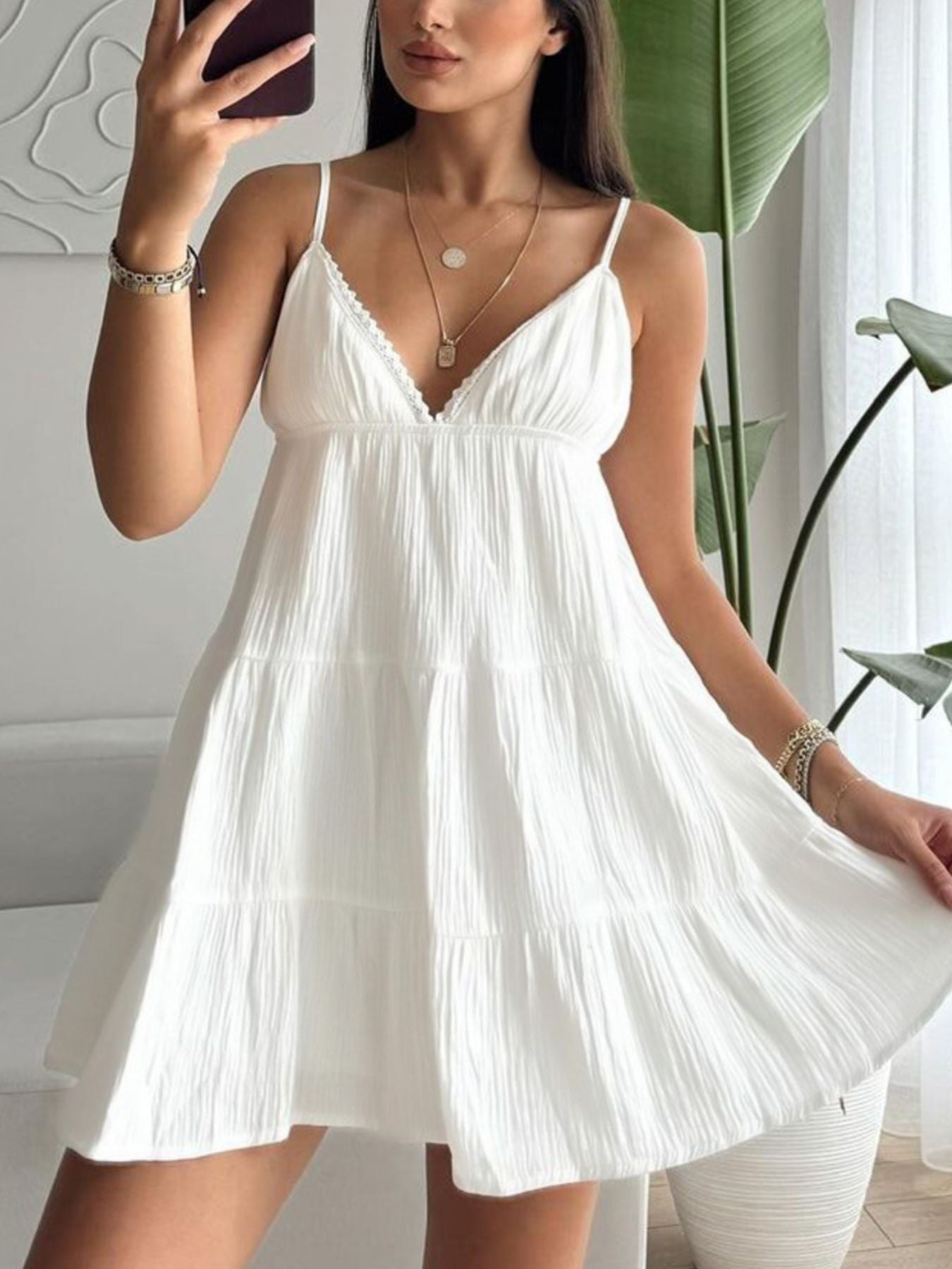 Woman wearing a white dress indoors with a plant in the background