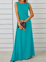 Woman wearing a teal sleeveless dress holding a black clutch against a light wooden background