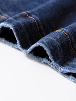 Close-up of blue denim fabric with visible stitching on a white background