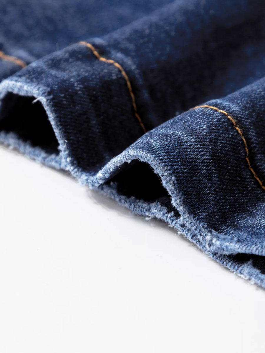 Close-up of blue denim fabric with visible stitching on a white background