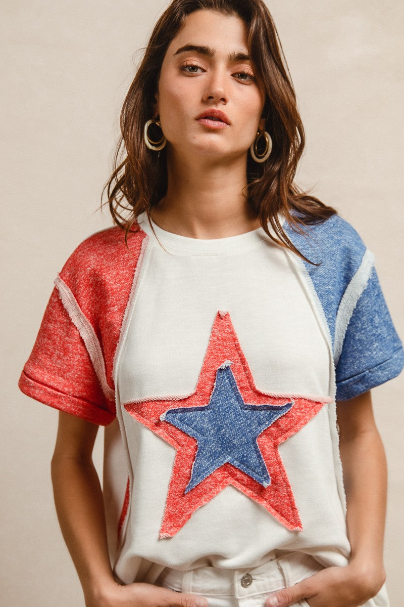 Woman wearing a colorful star-patterned top against a neutral background