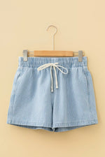 Blue striped shorts on a hanger against a beige background