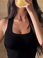 Person wearing a black sleeveless top with a blurred background