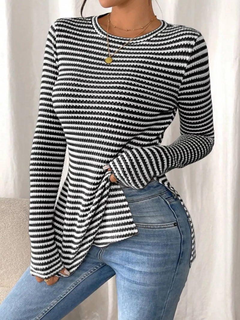 Person wearing a black and white striped sweater and blue jeans against a neutral background