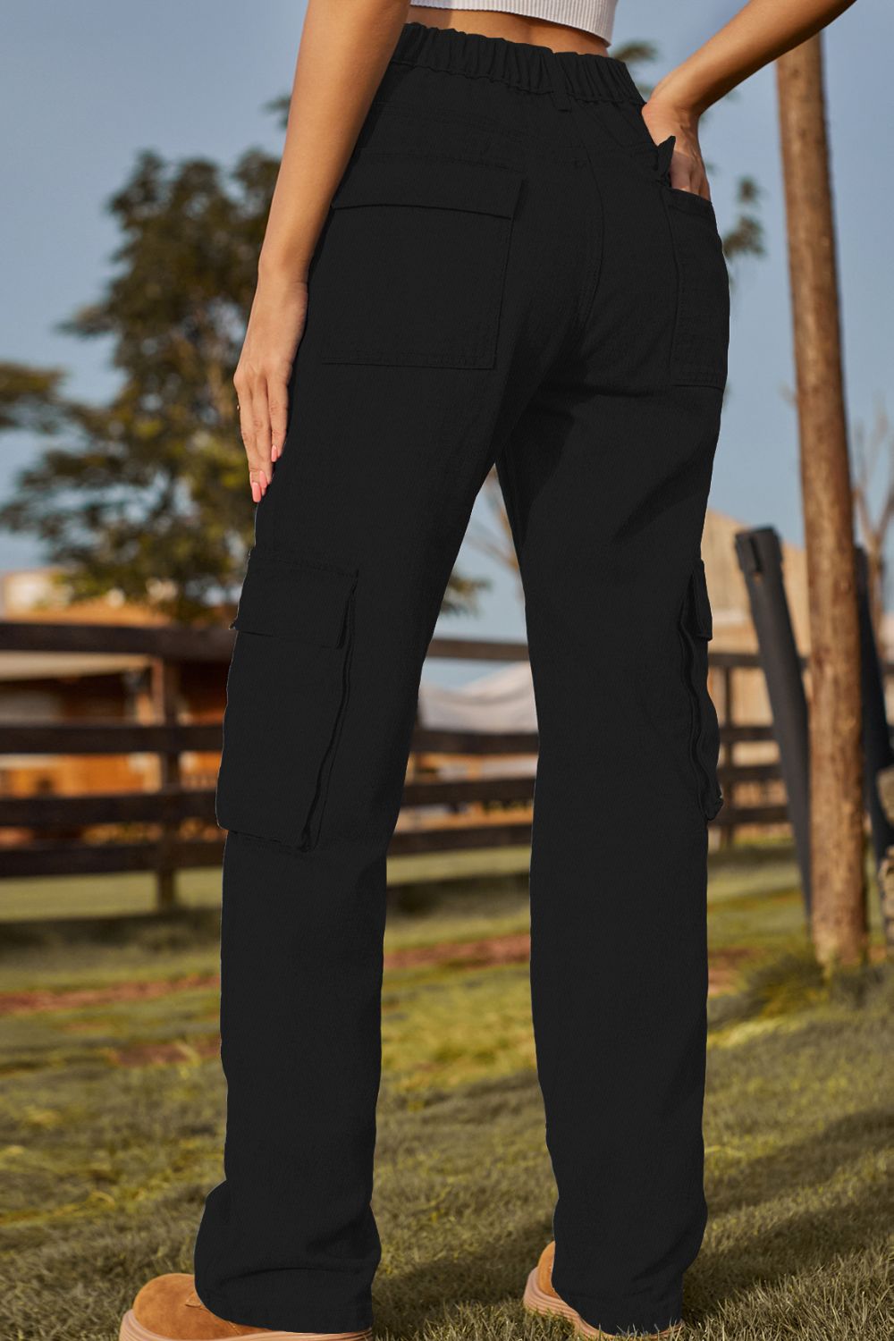 Person wearing black cargo pants with a blurred outdoor background