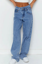 Person wearing blue jeans and white sneakers on a white background