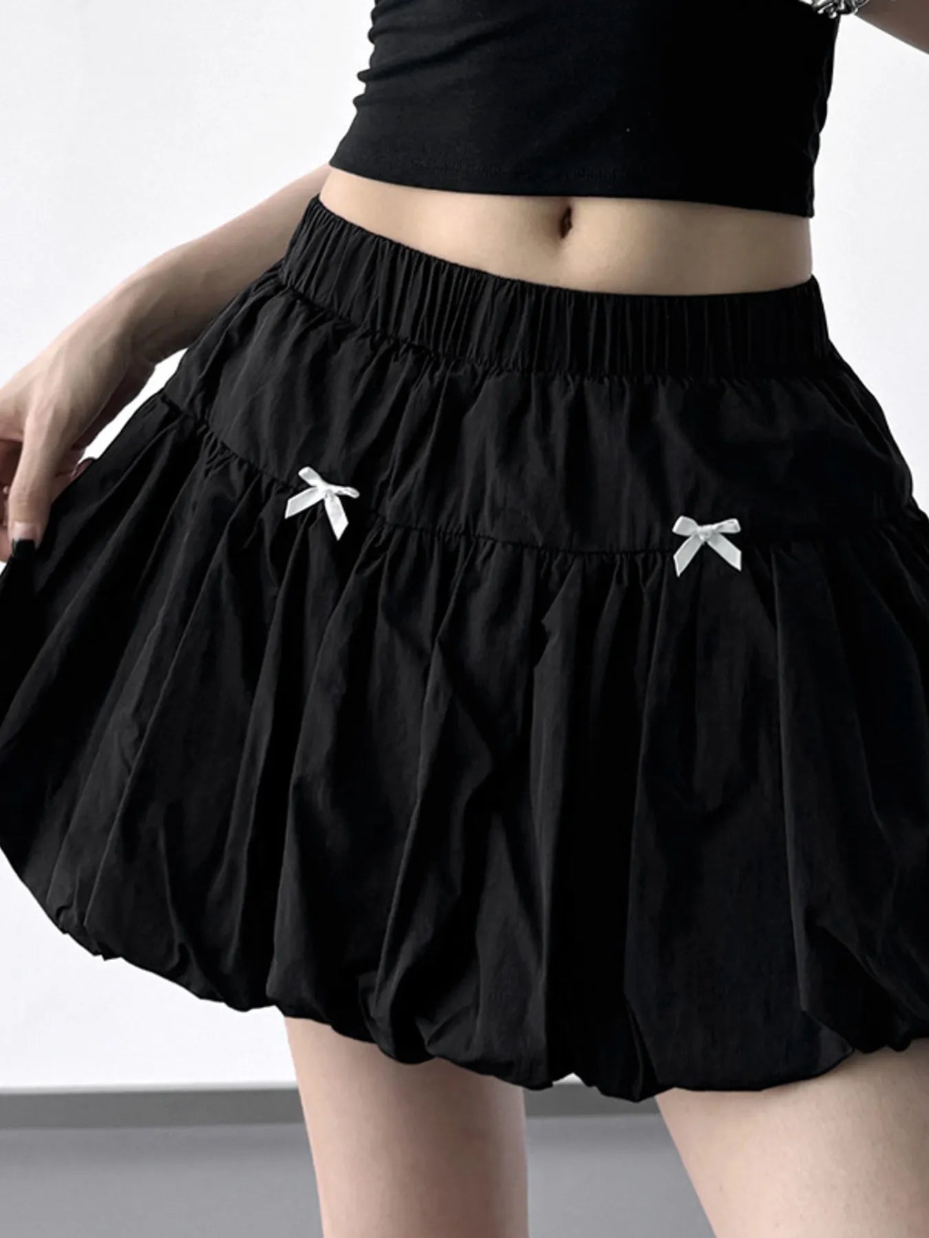Black skirt with white bow details worn by a person on a plain background